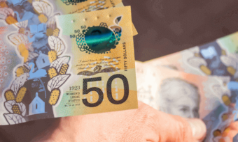 Man handing over pile of $50 in Australian notes.