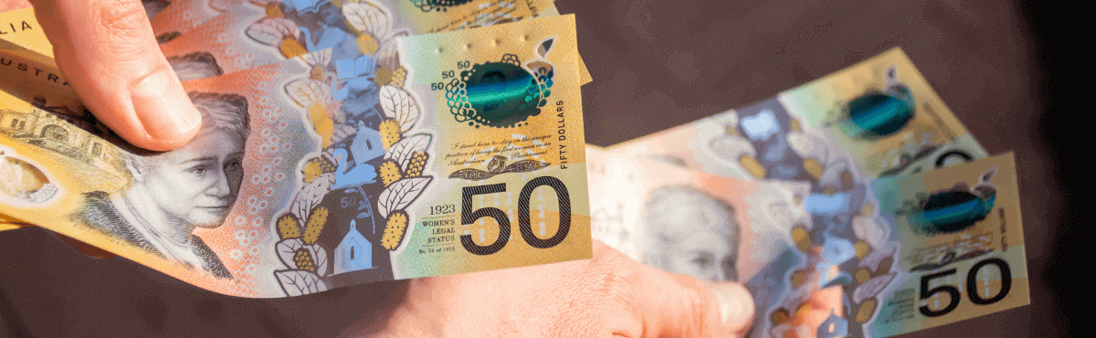 Man handing over pile of $50 in Australian notes.