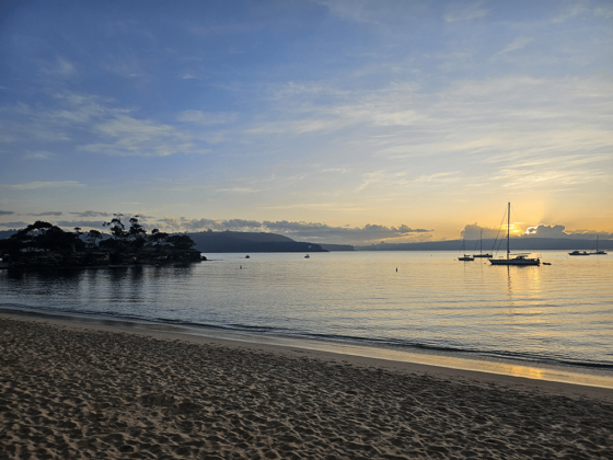 Beach and skyline at dawn, with boats in distance.