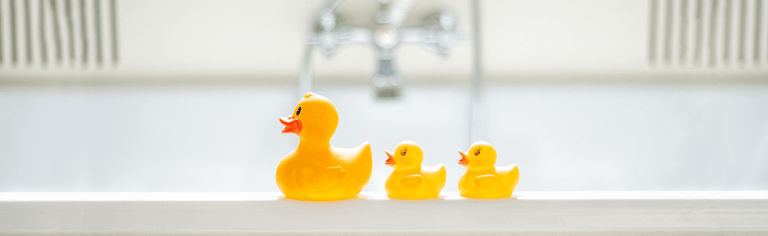 Yellow rubber ducks on the side of a white bath tub