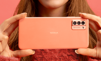 Close-up of woman in holding peach Nokia smartphone