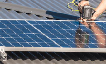 person drilling solar panel on roof