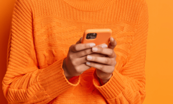 Close-up of hands using orange mobile phone