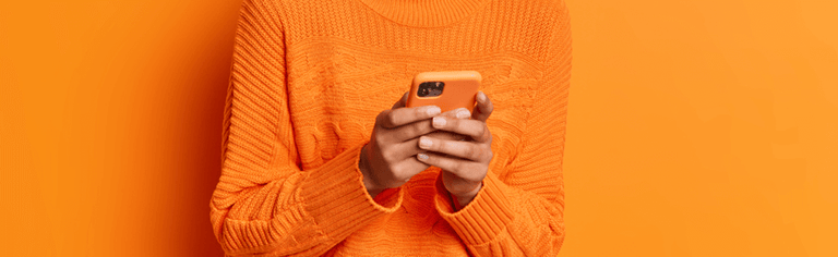 Close-up of hands using orange mobile phone
