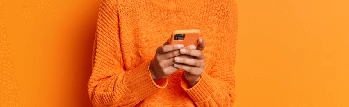 Close-up of hands using orange mobile phone