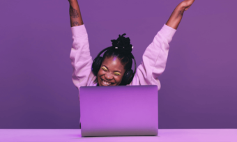 Happy young Black woman in purple using laptop