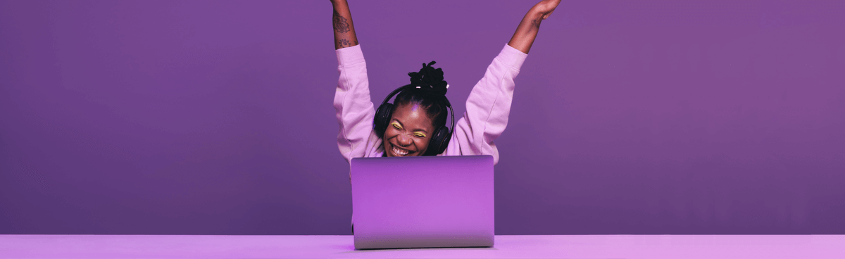 Happy young Black woman in purple using laptop