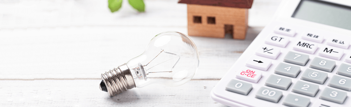 Lightbulb, calculator in front of small toy house