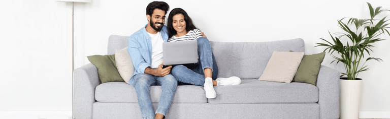 Happy couple using laptop at home