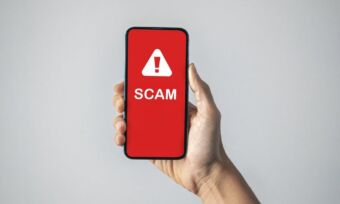 Photo of phone with the text scam and a warning symbol