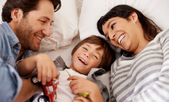 Mother and father and young child laughing and playing with toys